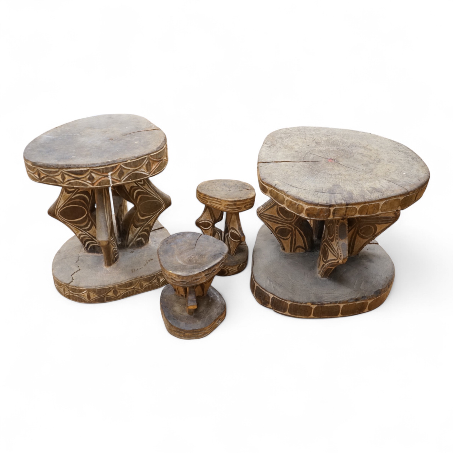 Papua New Guinea Sepik River, two tribal tables, each carved from a section of tree trunk, with circular top and base, the supports and edges incised and painted with geometric designs and two other small stools, largest